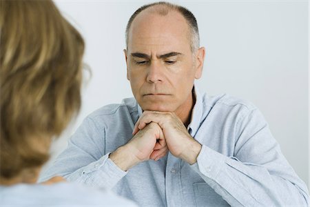 simsearch:695-03373745,k - Man resting chin on clasped hands, looking down, over the shoulder view Foto de stock - Royalty Free Premium, Número: 695-05768542