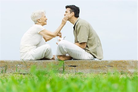 Senior woman and adult son sitting face to face outdoors, sharing take-out food Stock Photo - Premium Royalty-Free, Code: 695-05768576