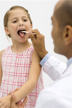 Médecin examinant la gorge de la jeune fille à l'aide d'un abaisse-langue Photographie de stock - Premium Libres de Droits, Code: 695-05768775