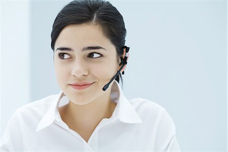 Young woman wearing headset, looking away, portrait Stock Photo - Premium Royalty-Free, Code: 695-05768802