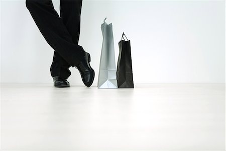Man standing next to shopping bags, cropped view of feet, low angle view Stock Photo - Premium Royalty-Free, Code: 695-05768816