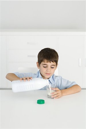 Boy pouring milk into empty glass Fotografie stock - Premium Royalty-Free, Codice: 695-05768827