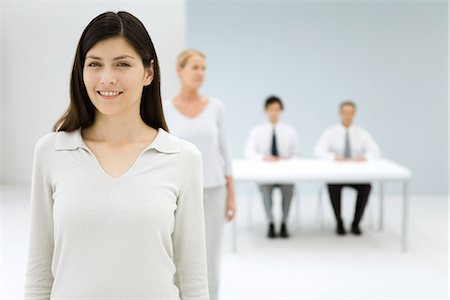 Professional woman smiling at camera, colleagues in background Foto de stock - Sin royalties Premium, Código: 695-05768823