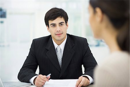 Businessman sitting at desk, listening to female client Stock Photo - Premium Royalty-Free, Code: 695-05768862