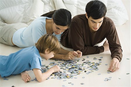 Family lying on floor, putting together jigsaw puzzle Stock Photo - Premium Royalty-Free, Code: 695-05768882