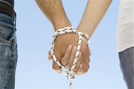 simsearch:633-02645515,k - Couple's hands bound together with rope, close-up Stock Photo - Premium Royalty-Free, Code: 695-05768938