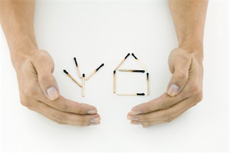 Hands protecting burnt matches arranged in shape of house and tree Stock Photo - Premium Royalty-Free, Code: 695-05768946