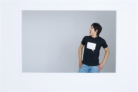 studio graphic - Jeune homme portant tee-shirt imprimé avec bulle mot vide, criant, mains sur les hanches Photographie de stock - Premium Libres de Droits, Code: 695-05769005