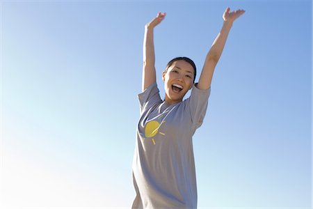 Woman with arms raised in the air, smiling at camera Stock Photo - Premium Royalty-Free, Code: 695-05769003