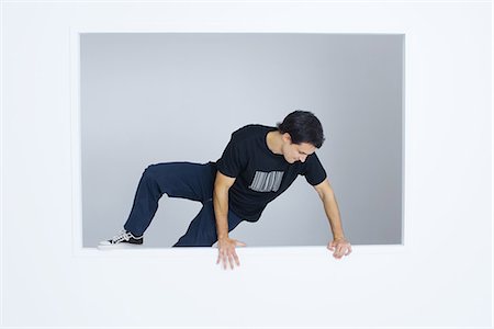 Man climbing over wall, wearing tee-shirt with bar code printed on it Foto de stock - Sin royalties Premium, Código: 695-05769013