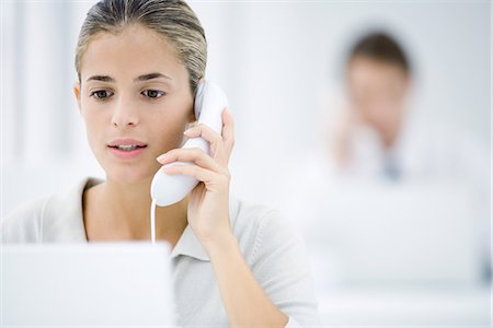 people shocked on phones - Young woman in office, using landline phone Stock Photo - Premium Royalty-Free, Code: 695-05769159