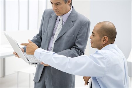 simsearch:695-05769165,k - Two businessmen looking at laptop computer together in office Stock Photo - Premium Royalty-Free, Code: 695-05769165