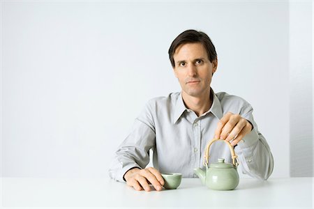 stereotype - Man sitting with teapot and teacup, looking at camera Stock Photo - Premium Royalty-Free, Code: 695-05769272