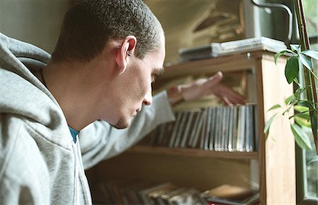 Young man selecting CD from collection on shelf Stock Photo - Premium Royalty-Free, Code: 695-05769353
