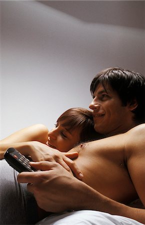 Young couple lying together in bed watching television, smiling Foto de stock - Sin royalties Premium, Código: 695-05769396