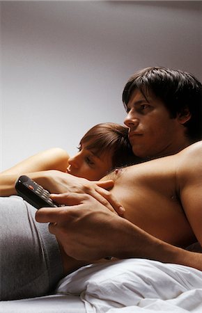 Young couple lying together in bed watching television Foto de stock - Sin royalties Premium, Código: 695-05769397