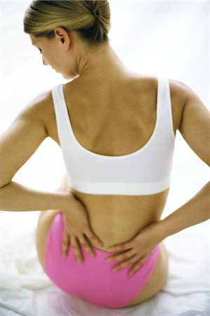 Woman sitting in underwear, holding lower back Foto de stock - Sin royalties Premium, Código: 695-05769613