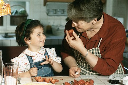 pastry display - Grandmother  and granddaughter cutting up strawberries, smiling at each other Stock Photo - Premium Royalty-Free, Code: 695-05769669