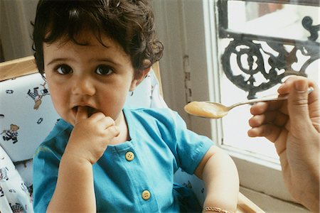 photo of mother feeding baby high chair - Little girl being spoon fed Stock Photo - Premium Royalty-Free, Code: 695-05769677