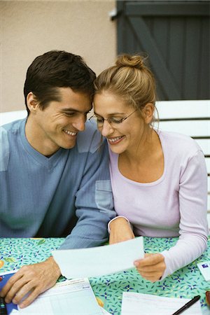 Couple sitting at table, discussing finances, both smiling Stock Photo - Premium Royalty-Free, Code: 695-05769705