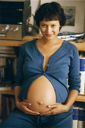 short haired women pregnant - Pregnant woman holding stomach, smiling at camera Stock Photo - Premium Royalty-Free, Code: 695-05769756