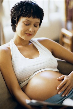 short haired women pregnant - Pregnant woman sitting on sofa, touching her stomach Stock Photo - Premium Royalty-Free, Code: 695-05769752