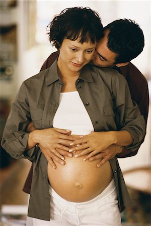 Man embracing pregnant woman from behind, both touching her stomach Stock Photo - Premium Royalty-Free, Code: 695-05769753