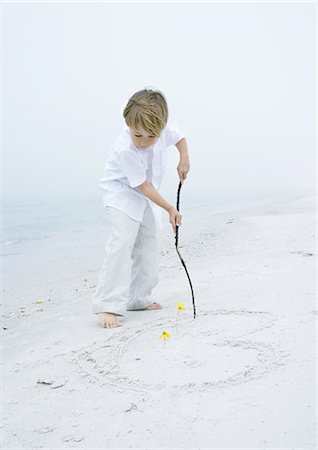 drawing on the sand with a stick - Little boy drawing heart in the sand at the beach Stock Photo - Premium Royalty-Free, Code: 695-05762839