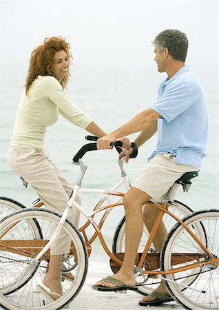 side view of a guy riding a bike - Couple face to face on bikes, on beach Stock Photo - Premium Royalty-Free, Code: 695-05762919