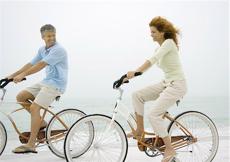 side view of a guy riding a bike - Couple riding bikes on beach Stock Photo - Premium Royalty-Free, Code: 695-05762922
