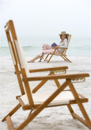 Woman sitting in beach chair, empty chair in foreground Stock Photo - Premium Royalty-Free, Code: 695-05762937