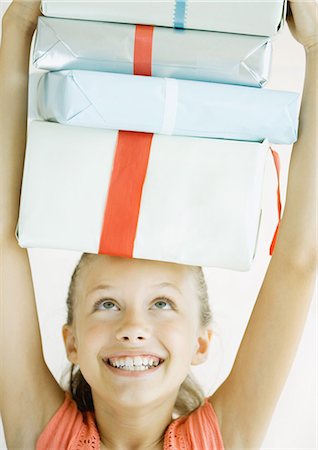 Girl holding stack of presents on head Stock Photo - Premium Royalty-Free, Code: 695-05763178