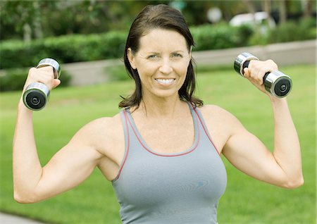 powerful mature female muscles - Woman lifting weights outdoors, smiling Stock Photo - Premium Royalty-Free, Code: 695-05763288