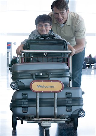 Man and boy pushing luggage cart Stock Photo - Premium Royalty-Free, Code: 695-05763293