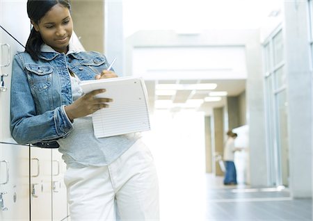 school jacket - Teen girl standing by locker, writing in notebook Stock Photo - Premium Royalty-Free, Code: 695-05763370