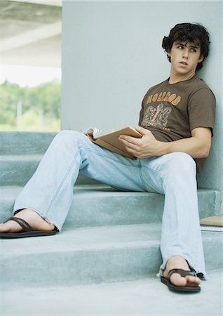 Young man sitting on steps with book Stock Photo - Premium Royalty-Free, Code: 695-05763430