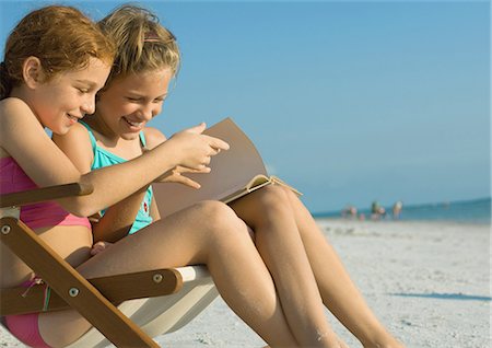 Girls reading book together on beach Stock Photo - Premium Royalty-Free, Code: 695-05763591