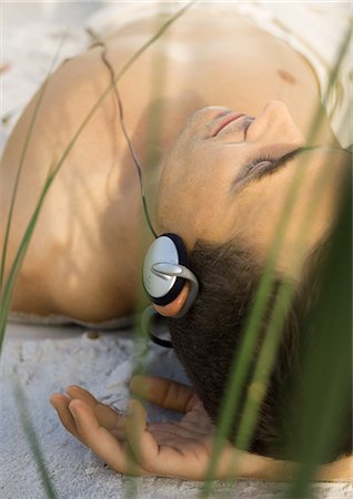 Man lying on sand, listening to headphones Stock Photo - Premium Royalty-Free, Code: 695-05763671