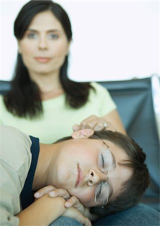 Boy sleeping on mother's lap in airport lounge Stock Photo - Premium Royalty-Free, Code: 695-05763963