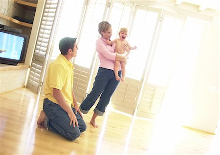 simsearch:695-03385318,k - Woman holding crying baby, man kneeling on floor Foto de stock - Royalty Free Premium, Número: 695-05774163
