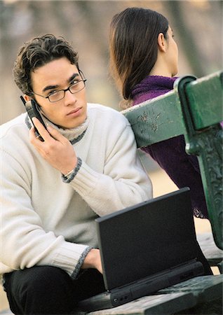 Homme assis sur un banc de parc avec le téléphone portable et ordinateur portable, femme assise sur l'autre côté du banc Photographie de stock - Premium Libres de Droits, Code: 695-05774490