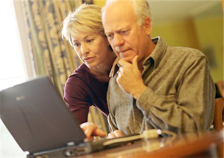 Mature couple, man using laptop, woman looking over shoulder Stock Photo - Premium Royalty-Free, Code: 695-05774672