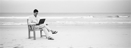 Man sitting in chair on beach using laptop, b&w, panoramic view Stock Photo - Premium Royalty-Free, Code: 695-05774742