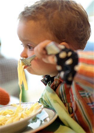 Baby eating pasta, side view. Stock Photo - Premium Royalty-Free, Code: 695-05774788