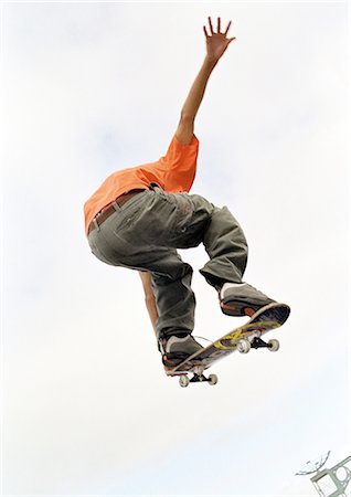 Young man on skateboard, jumping, mid-air, low angle, rear view. Stock Photo - Premium Royalty-Free, Code: 695-05775272