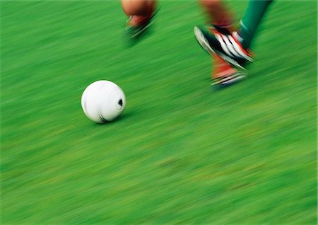 Feet of two soccer players running for ball, low section, blurred Stock Photo - Premium Royalty-Free, Code: 695-05775818