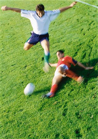 soccer tackle - Soccer player reaching for ball, opponent jumping over leg, blurred. Stock Photo - Premium Royalty-Free, Code: 695-05775824