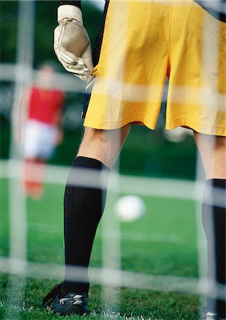 soccer goalkeeper backside - Goal keeper defending goal area when opponent is about to take penalty kick, seen from behind the goal. Stock Photo - Premium Royalty-Free, Code: 695-05775831