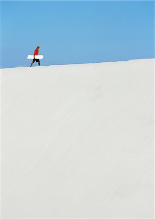 desert endurance - Man walking along crest of dune with sandboard Stock Photo - Premium Royalty-Free, Code: 695-05775901