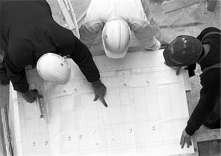 simsearch:632-03652160,k - Three people with hard hats, examining blueprint, elevated view, b&w Stock Photo - Premium Royalty-Free, Code: 695-05776077